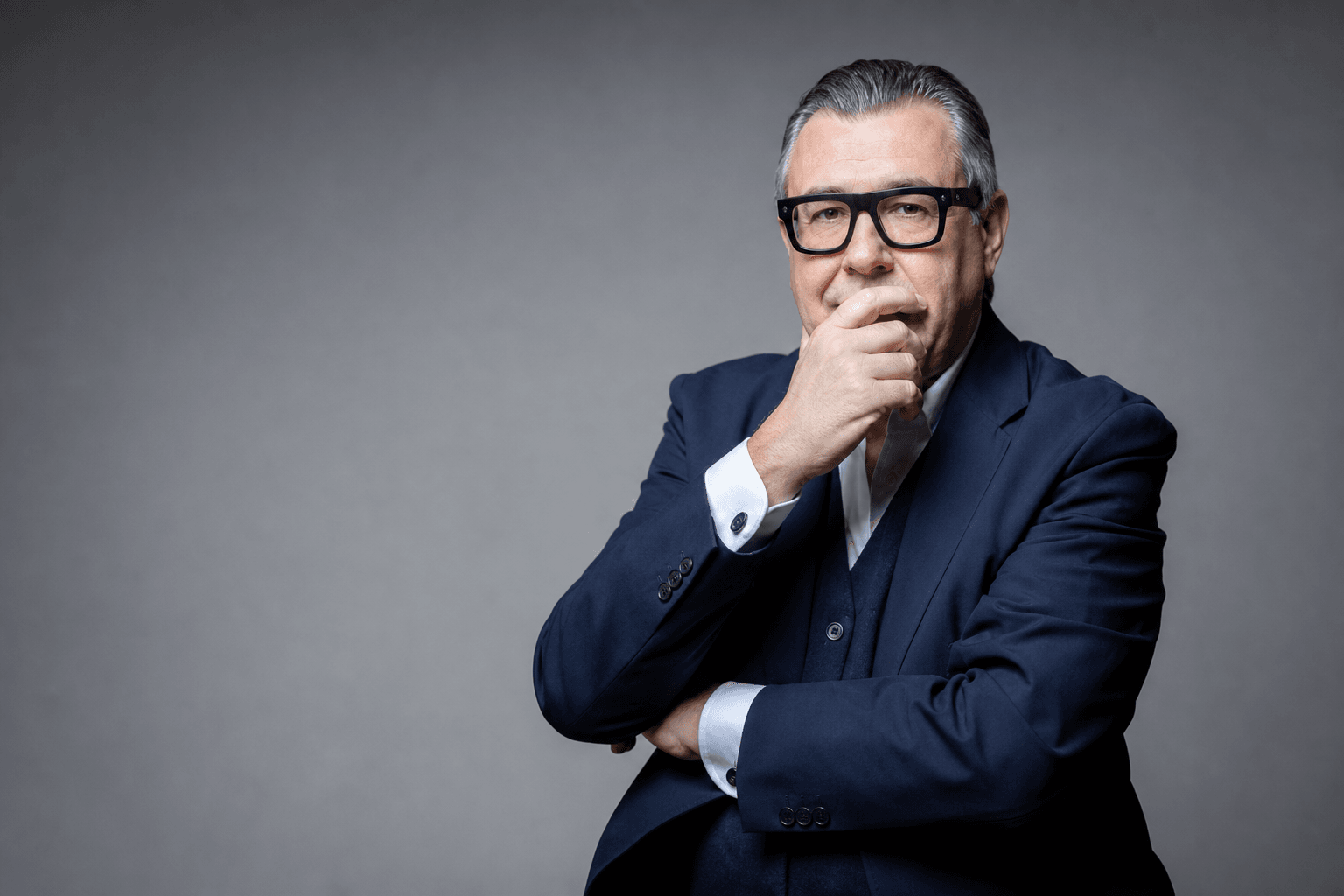 Hombre profesional con traje azul marino y gafas, brazos cruzados